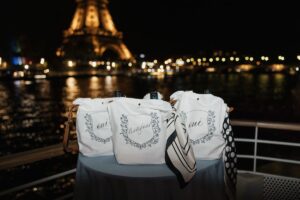 Detail shot of three personalized tote bags in front of the Eiffel Tower from Hannah Godwin and Dylan Barbour's Welcome party