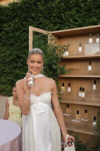 Hannah Godwin posing with a custom engraved room spray at her rehearsal dinner