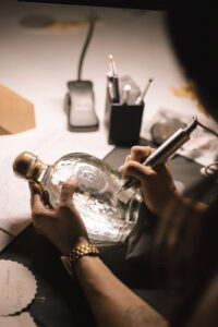 Close up shot of Cat Lauren Calligraphy engraving a tequila bottle to be used as a custom wedding favor at Chable Yucatan